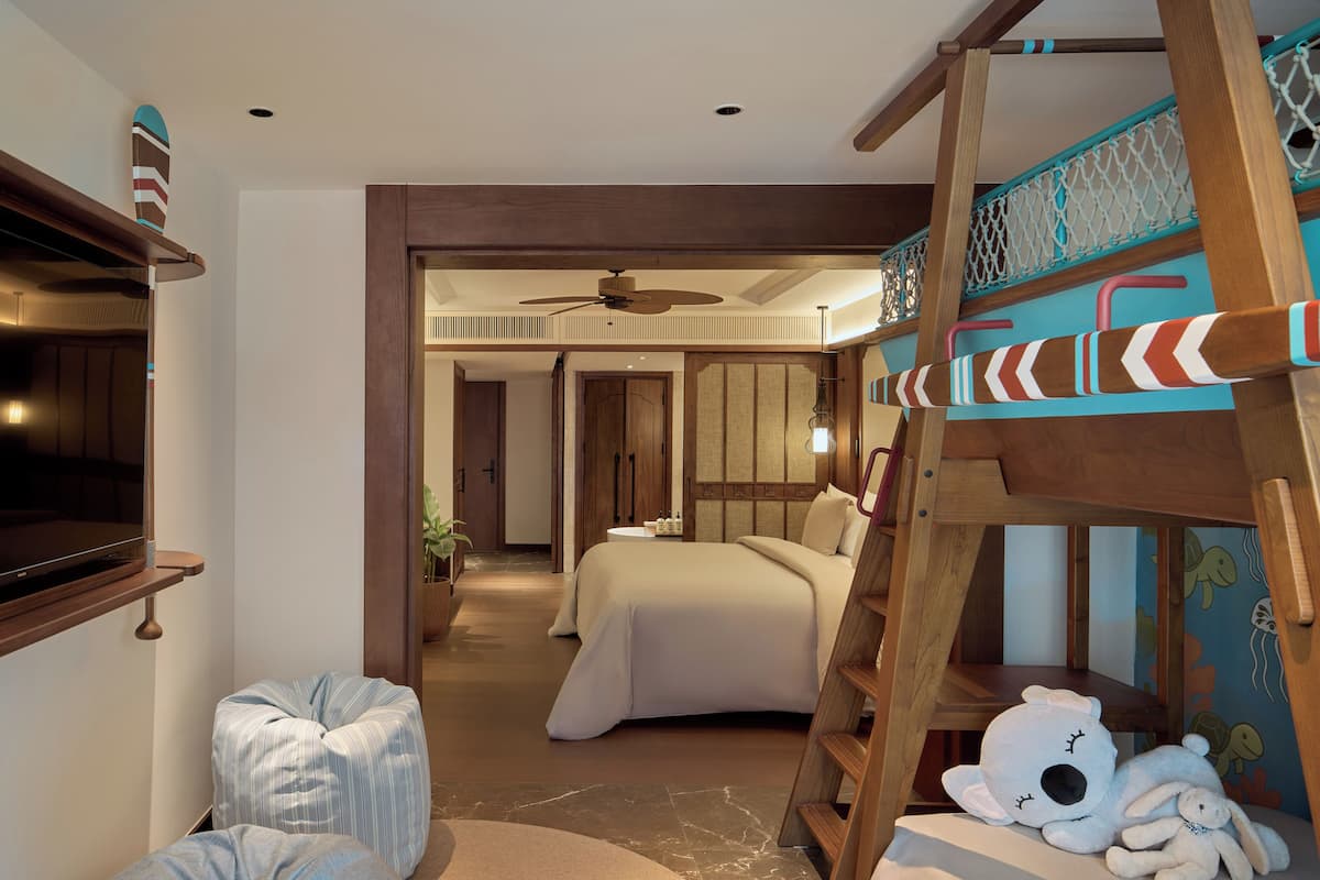 Ein Schlafzimmer mit Etagenbett, Deckenventilator, Nachttisch und einem an der Wand montierten Fernseher.