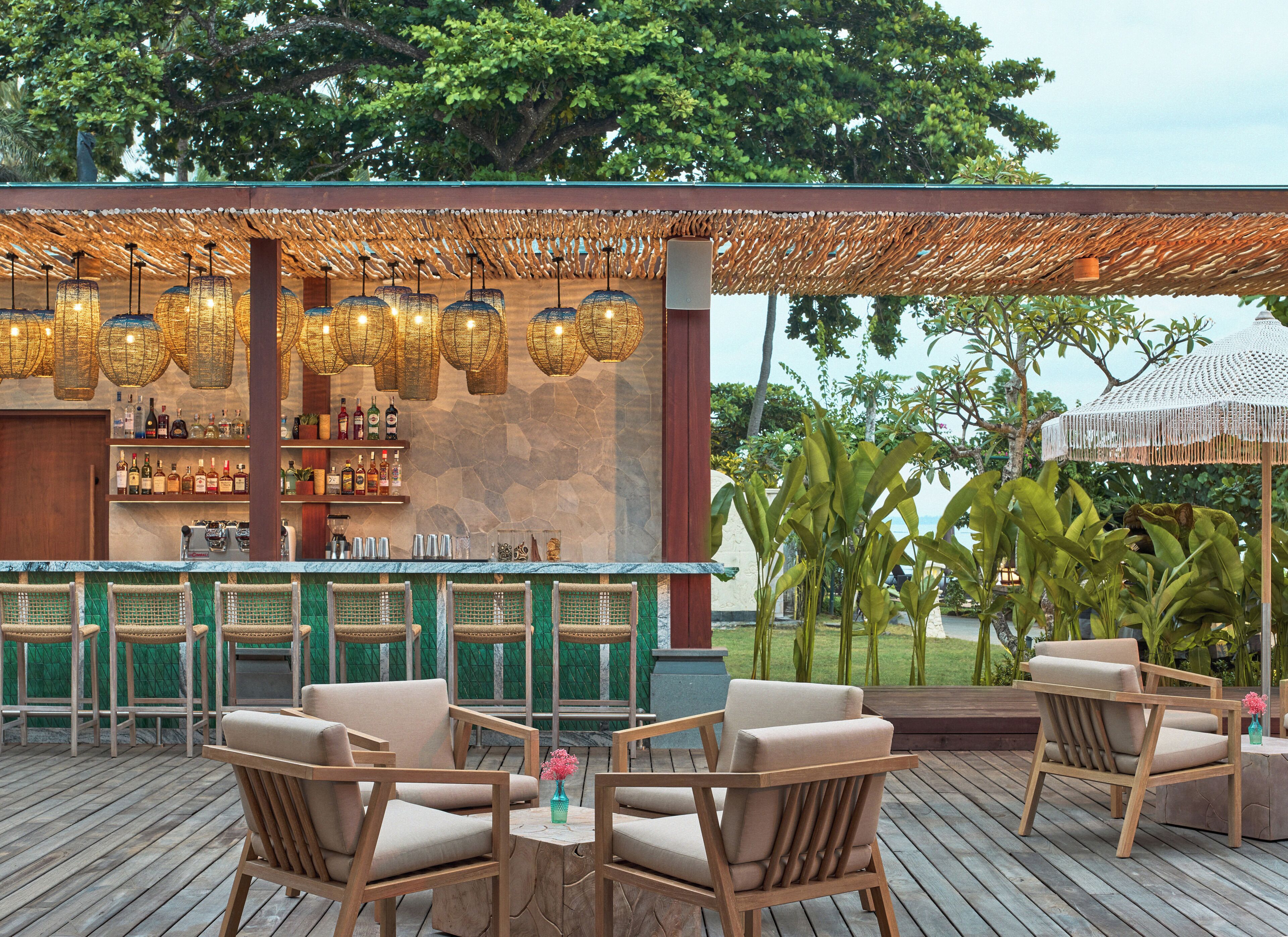 An outdoor bar area with wicker chairs, a bar counter, and hanging wicker light fixtures.