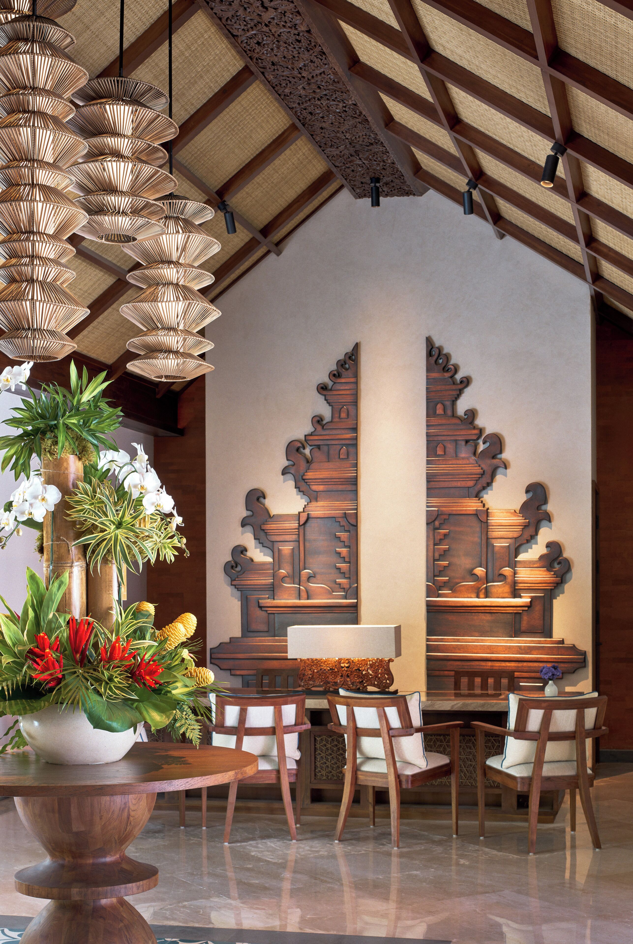 A traditional interior with a wooden table, chairs, a decorative wall, and hanging lamps.
