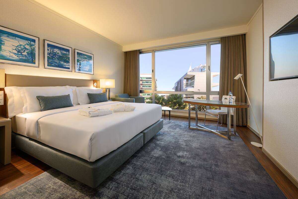 Una habitación de hotel moderna con una cama grande, un escritorio y vistas a la ciudad.