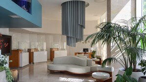 Un moderno vestíbulo de hotel con un sofá curvo, una recepción y plantas en macetas.