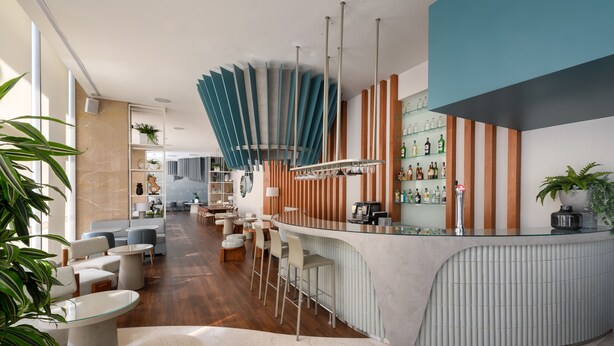 A modern bar area with a curved counter, bar stools, and a seating area with tables and chairs.