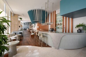 A modern bar area with a curved counter, bar stools, and a seating area with tables and chairs. - Meliá Lisboa Oriente (Lisbon)