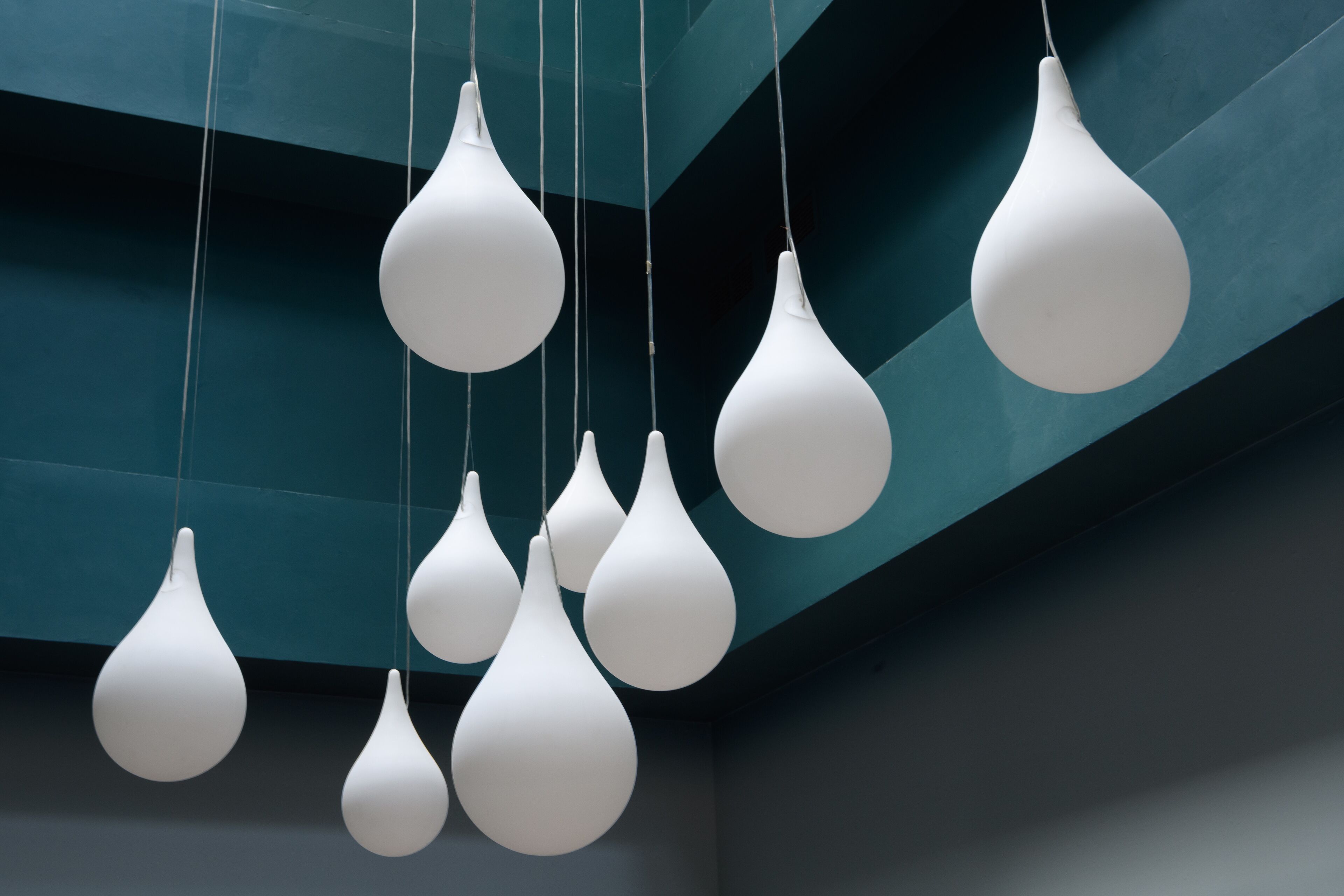 A ceiling with multiple white pendant lights hanging in a modern, geometric pattern.