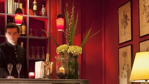 A bar area with a wooden counter, chairs, and a table with a candle and decorative items.