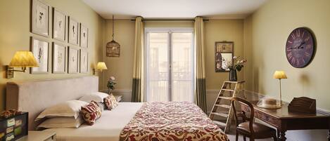 A hotel room with a bed, bedside lamps, a desk, a chair, and a large window with curtains.