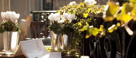 A table with a menu, a vase with white flowers, and a potted plant.