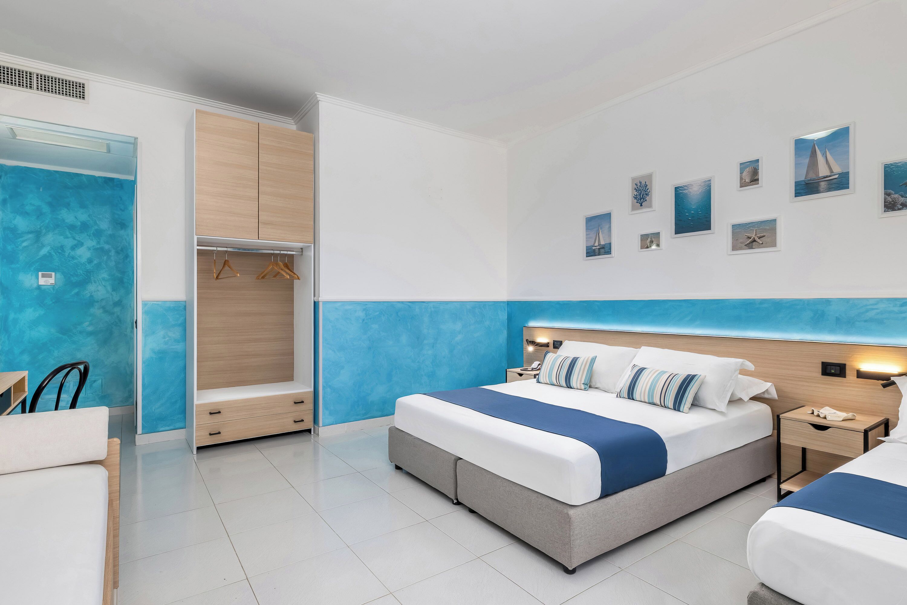 Ein modernes Hotelzimmer mit einem großen Bett, einem Kleiderschrank, einem Schreibtisch und einem Sessel.