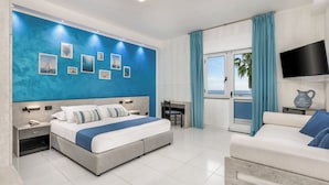 A modern bedroom with a large bed, a desk, a TV, and a view of the sea. - Hotel Blu Eden - Calabria oltre il Mare - Adults Only (Praia a Mare)
