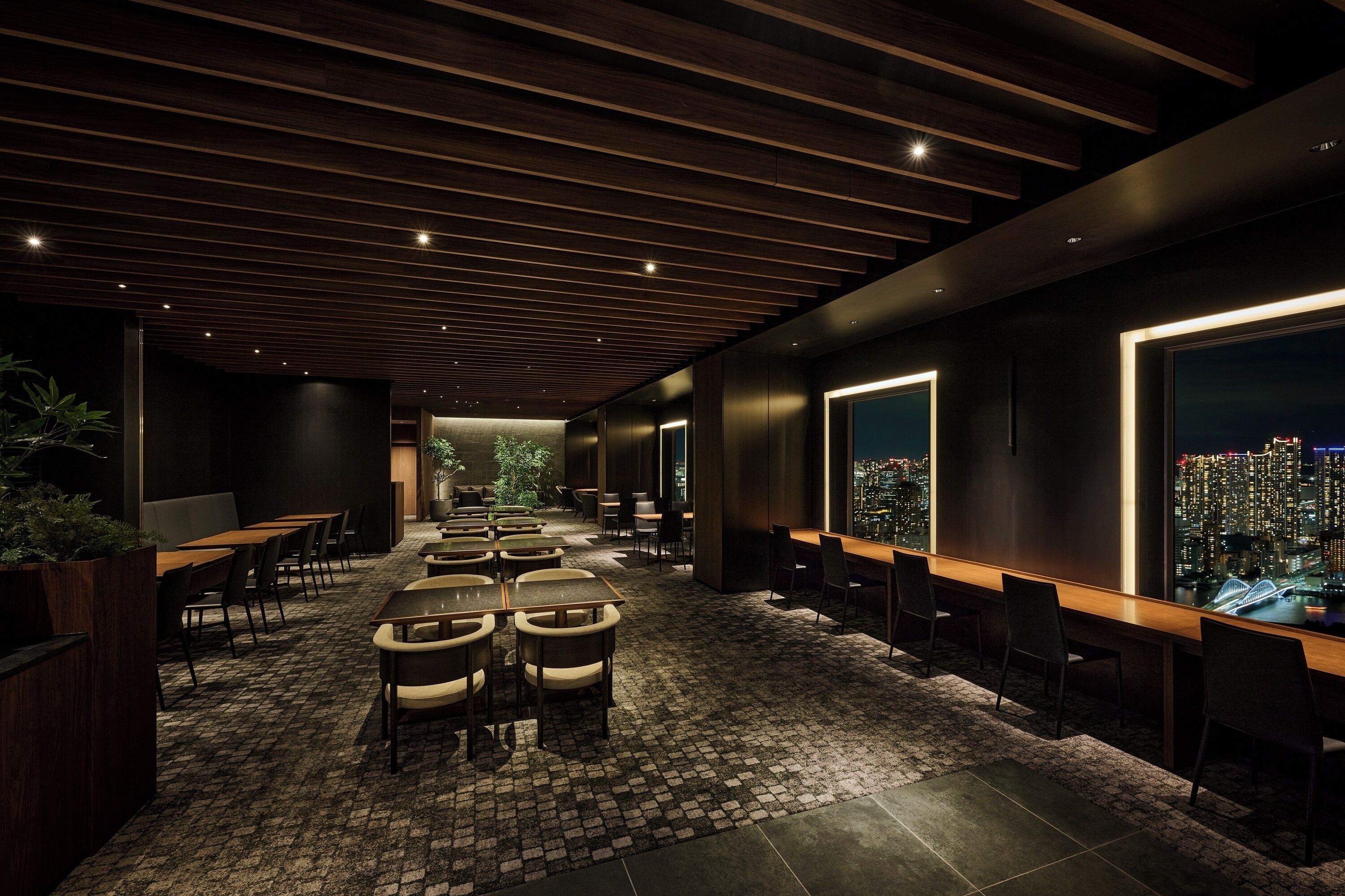 A modern interior with a brick floor, wooden ceiling, and seating areas with tables and chairs.