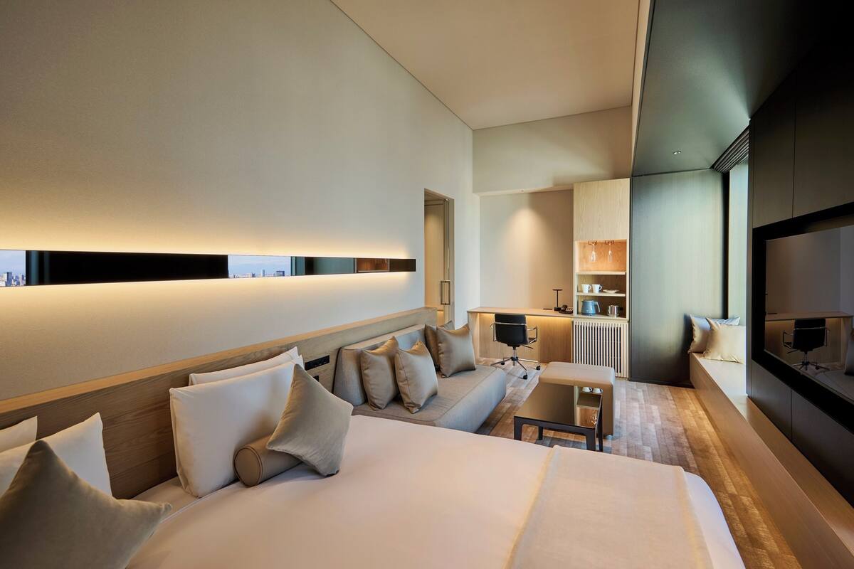Een moderne hotelkamer met een groot bed, een bank, een klein tafeltje, een bureau en een televisie.