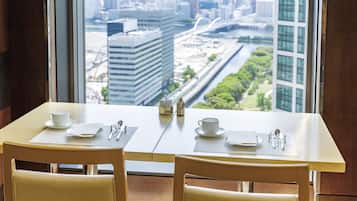 A dining table with two chairs, a cup, and cutlery set.