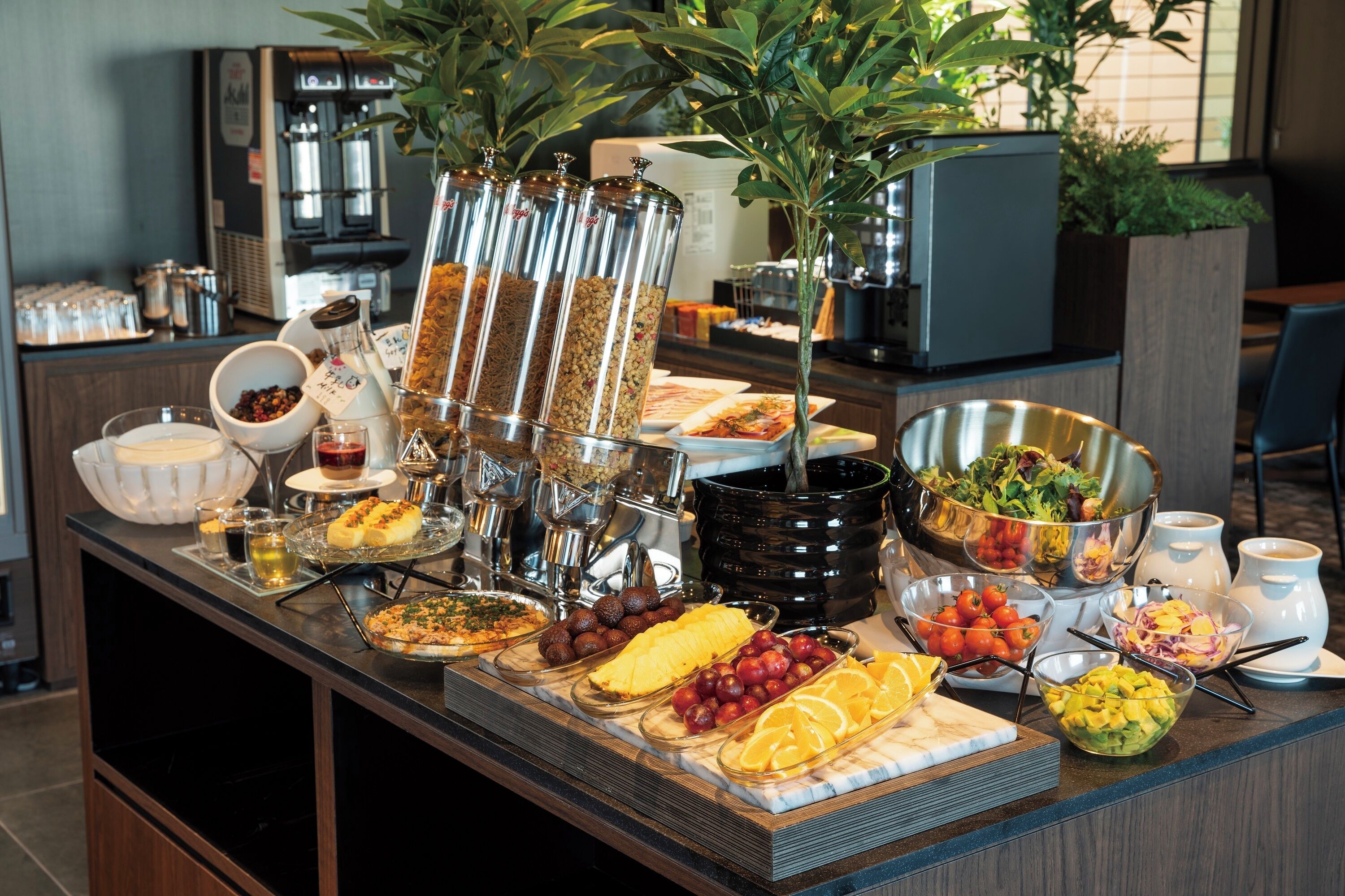 Ein reichhaltiges Buffet mit verschiedenen Speisen und Getränken, darunter Früchte, Salate und eine Kaffeemaschine.