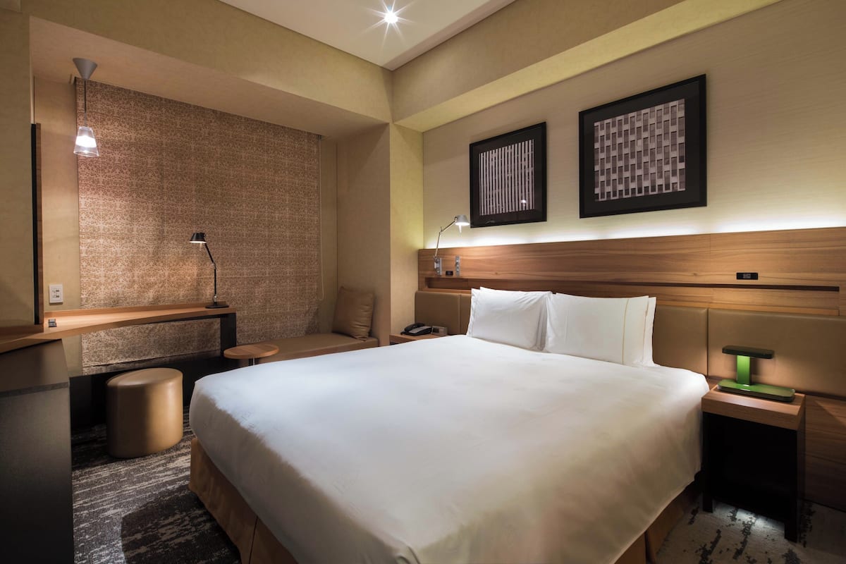 Een hotelkamer met een groot bed, nachtkastjes, een bureau en een stoel.