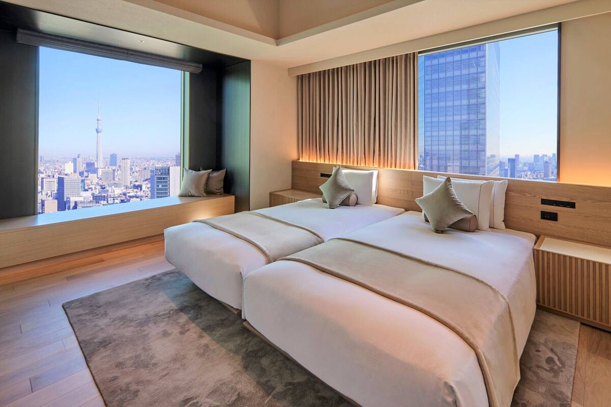 Een moderne hotelkamer met een groot bed, uitzicht over de stad en een groot raam.