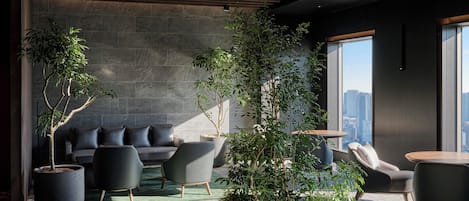 A modern lounge area with a sofa, chairs, and potted plants.