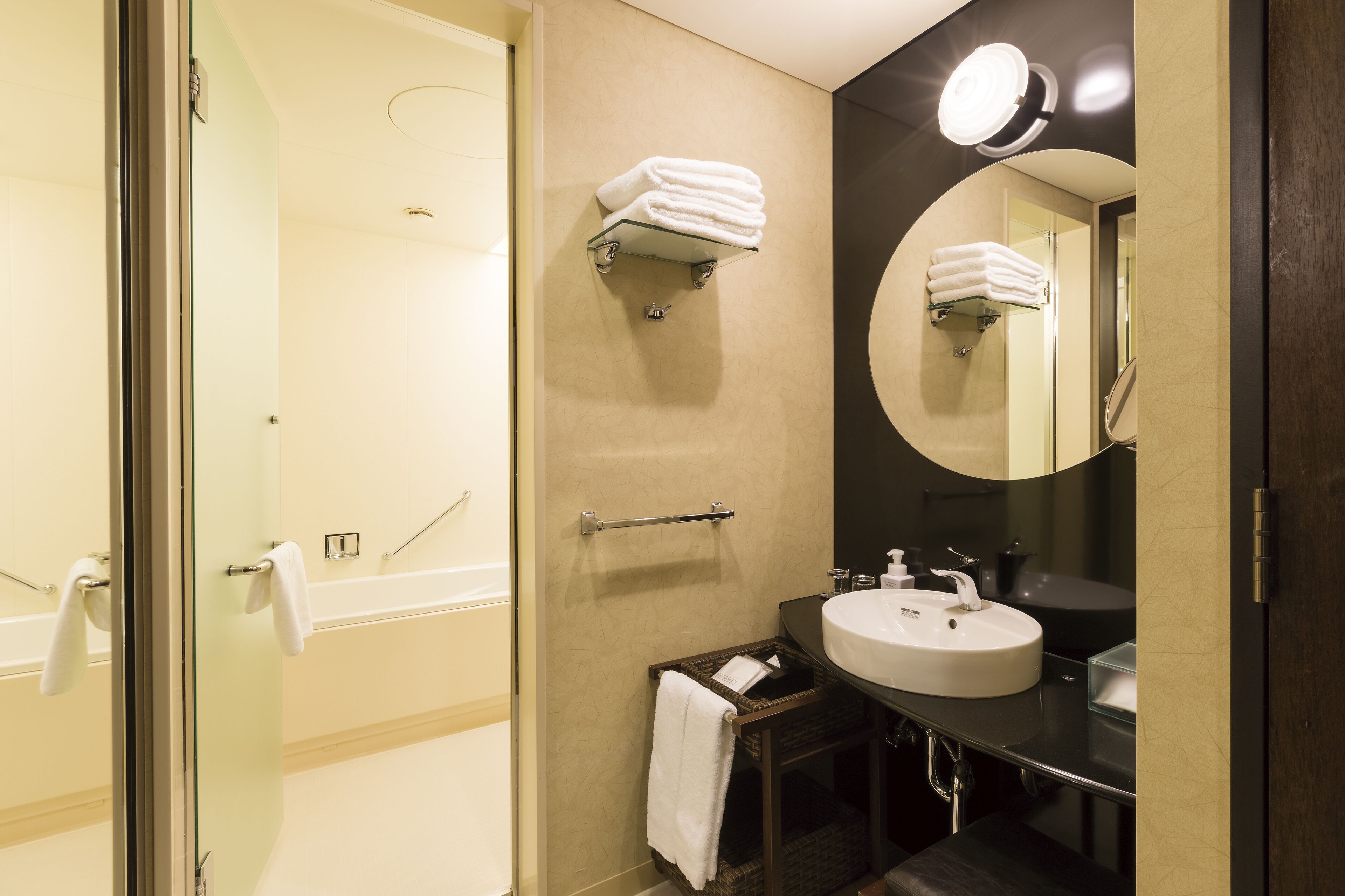 Une salle de bain avec une porte de douche en verre, un lavabo avec un miroir et un porte-serviettes.