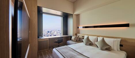 A modern hotel room with a large bed, a desk, and a view of the city.