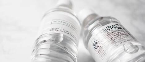 Dos botellas de agua transparentes de plástico, una con la etiqueta 'ROYAL PARK HOTEL' y la otra con un símbolo de reciclaje.