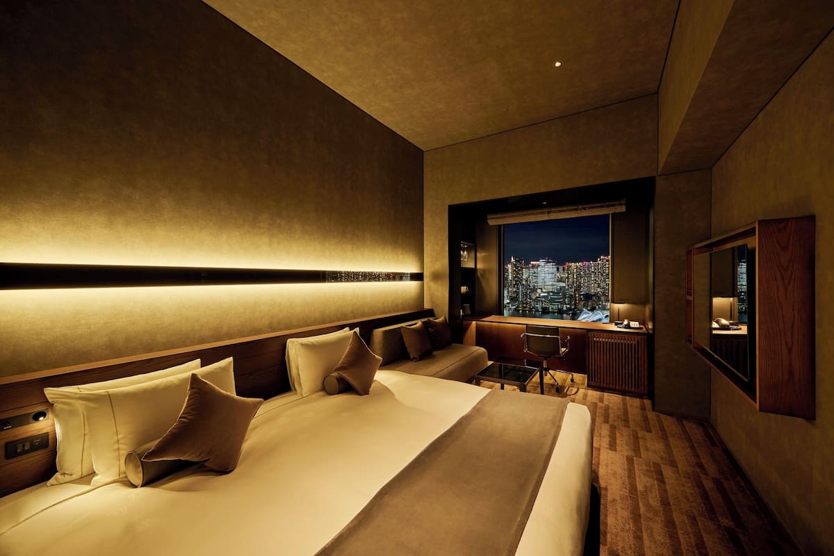 Een moderne hotelkamer met een groot bed, een bureau en uitzicht over de stad.