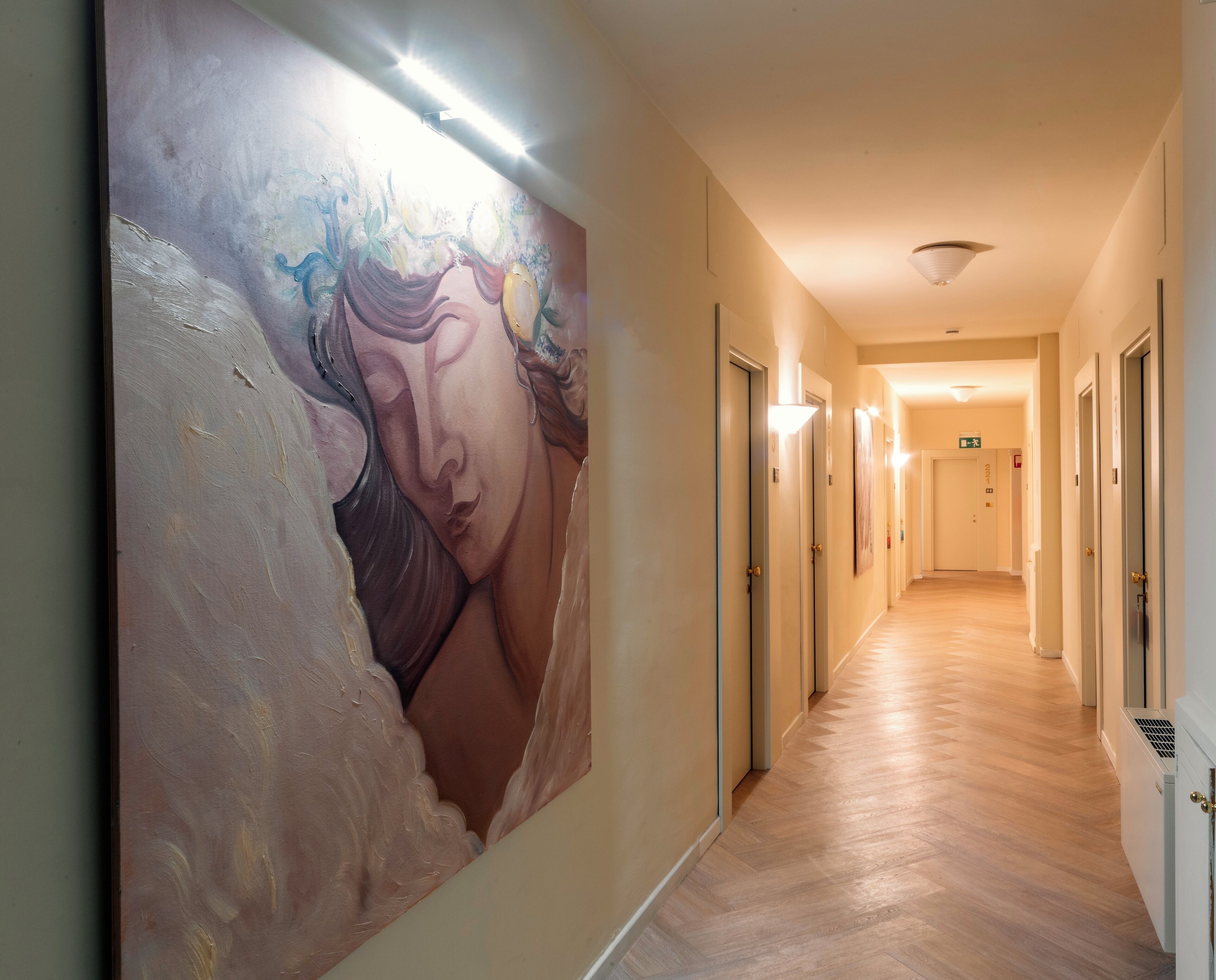 Un corridoio con un grande murale sulla parete sinistra, porte su entrambi i lati e un pavimento in legno.