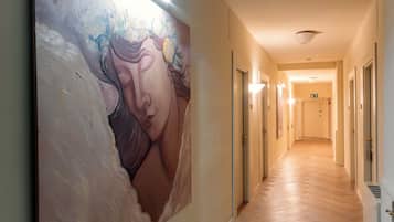 Un corridoio con un grande murale sulla parete sinistra, porte su entrambi i lati e un pavimento in legno.