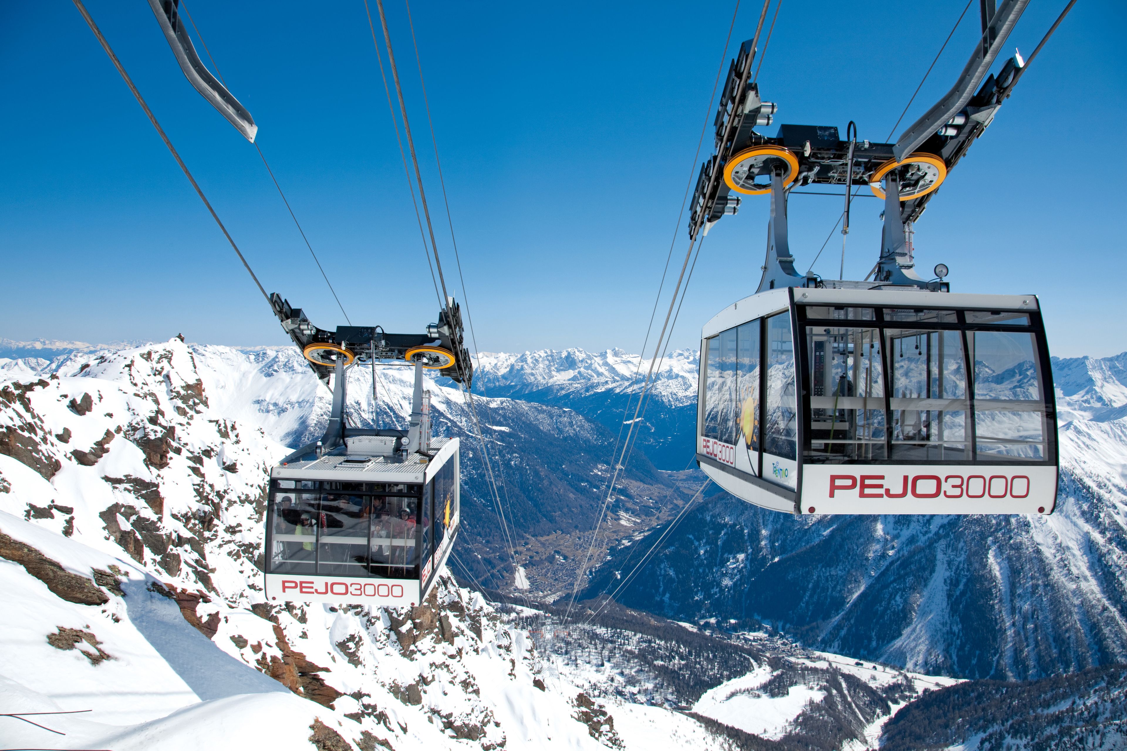 A cable car system with cabins labeled "PEJO3000" against a mountainous backdrop.
