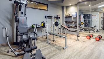 A gym with various exercise equipment, including a treadmill, weight bench, and dumbbells.
