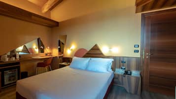 A hotel room with a bed, desk, chair, and a wooden wardrobe.
