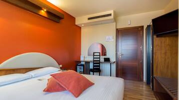 A hotel room with a bed, a desk, and a wardrobe.