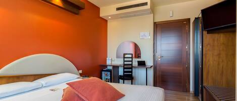 A hotel room with a bed, a desk, and a wardrobe.