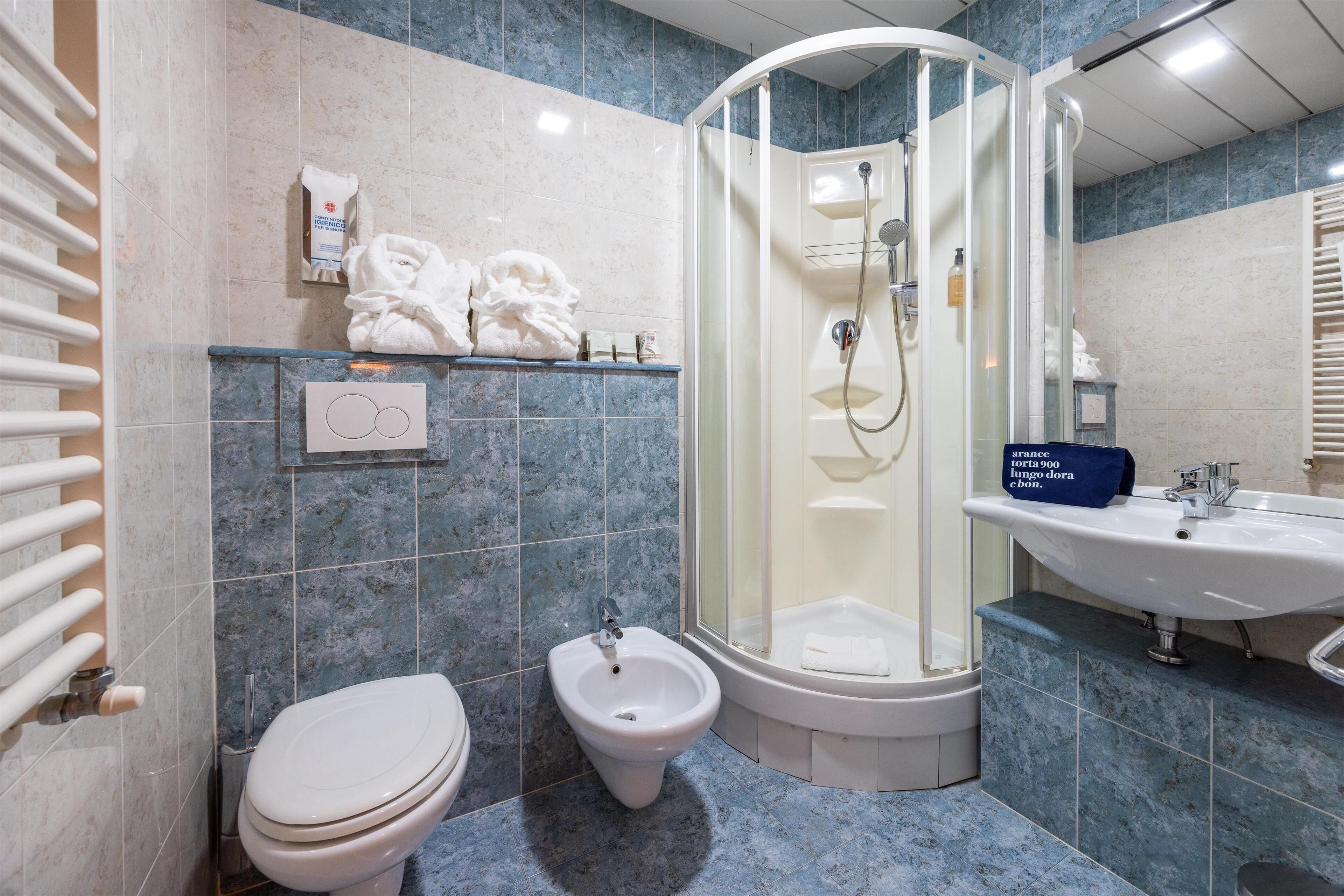 A bathroom with a toilet, bidet, shower, and sink.