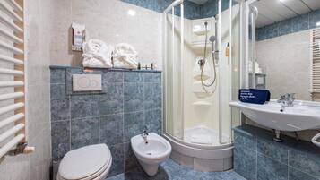 A bathroom with a toilet, bidet, shower, and sink.