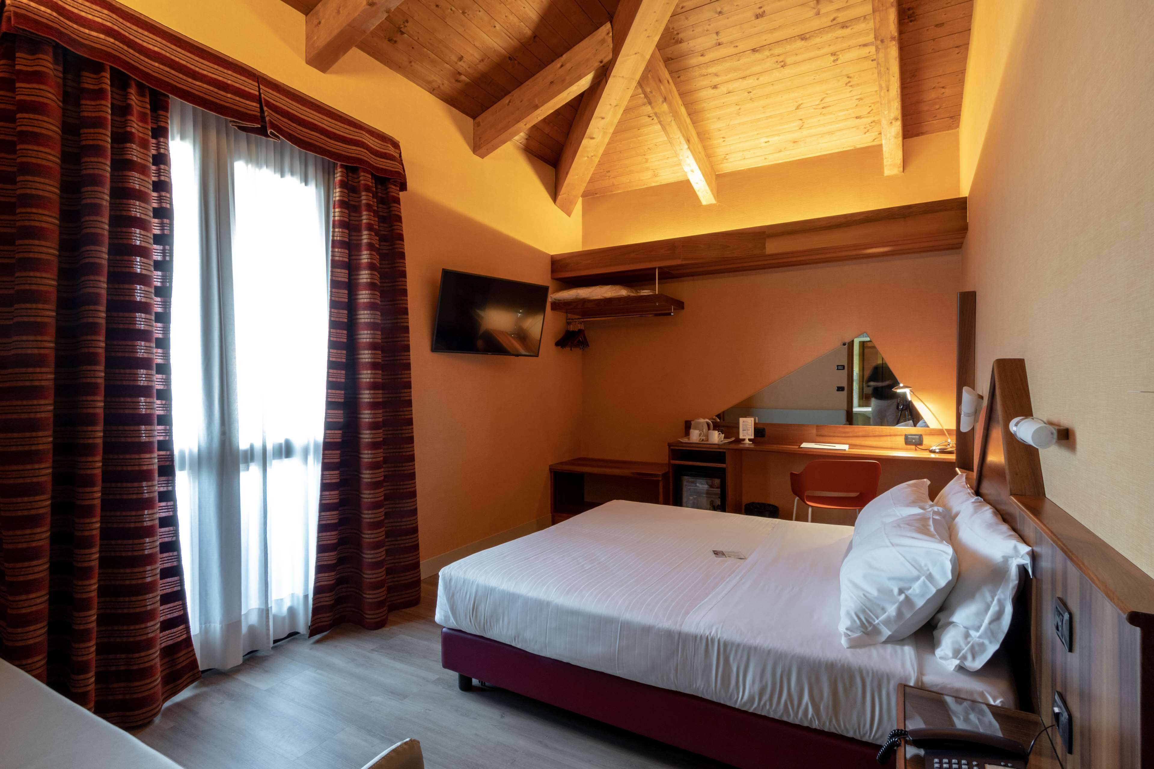Een hotelkamer met een bed, bureau, stoel en telefoon.