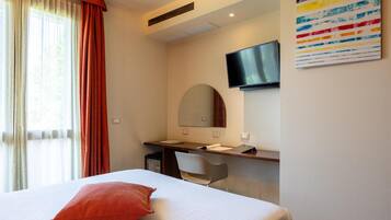 Una habitación de hotel con cama, escritorio, silla, televisor y una obra de arte colorida en la pared.