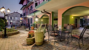 An outdoor café with tables and chairs, potted plants, and a street view in the background. - La Villa, Sure Hotel Collection by Best Western (Ivrea)