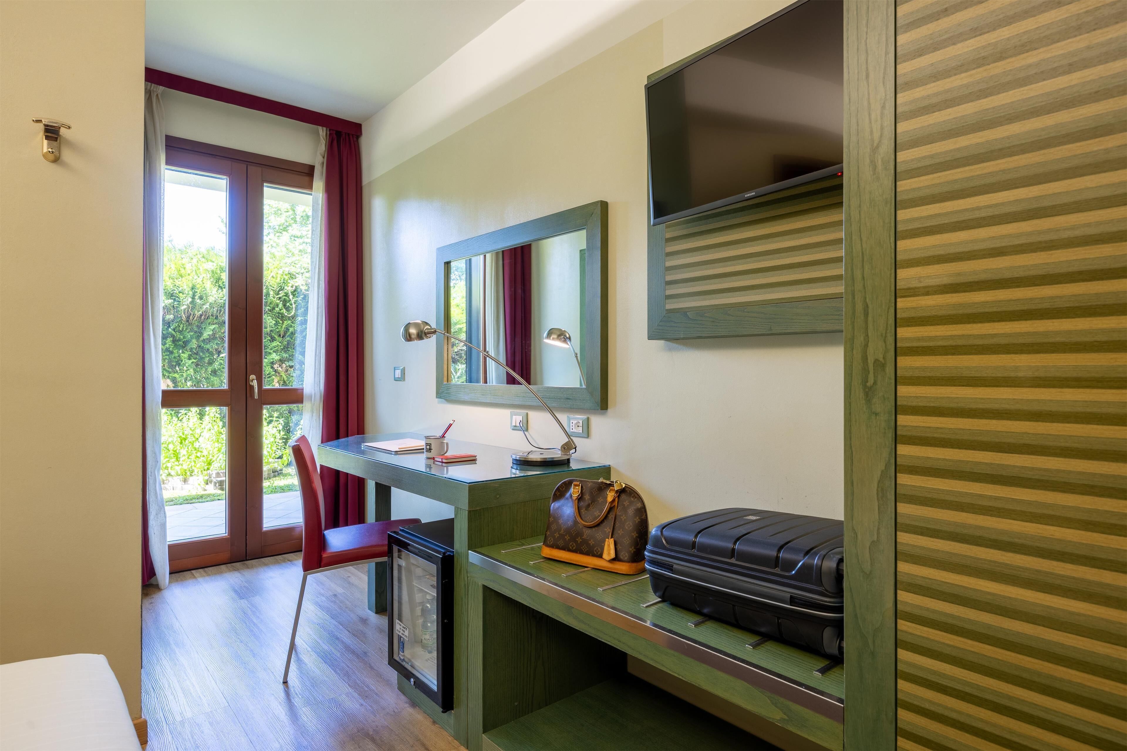A room with a desk, chair, and a suitcase.
