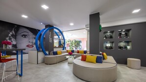 A modern lounge area with a curved sofa, a round coffee table, and a wall-mounted circular mirror. - La Villa, Sure Hotel Collection by Best Western (Ivrea)