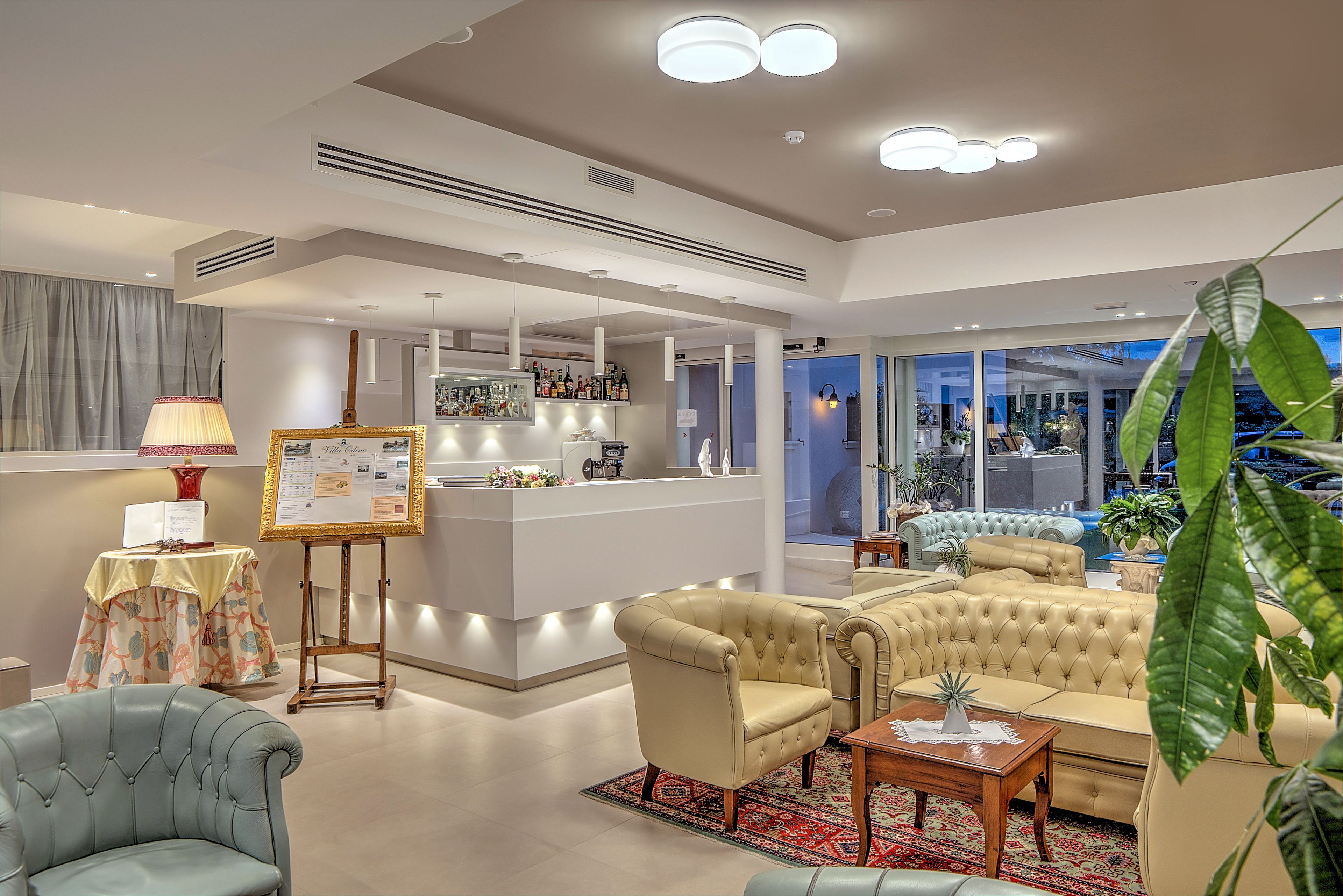 A modern living room with a bar area, leather sofas, and a large window.