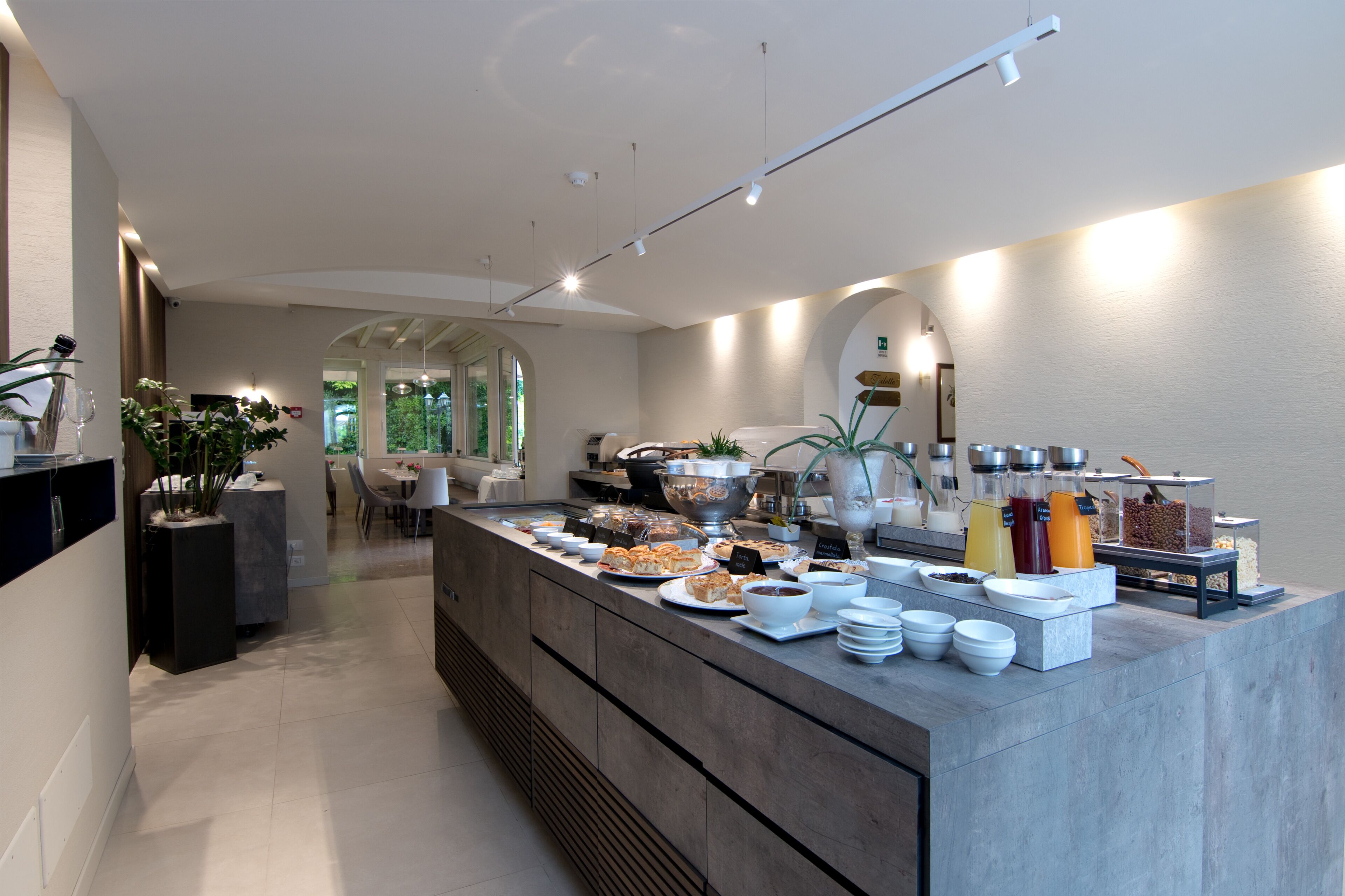 A modern breakfast bar with a variety of food and drink options, a seating area with chairs, and a view of the outdoors.
