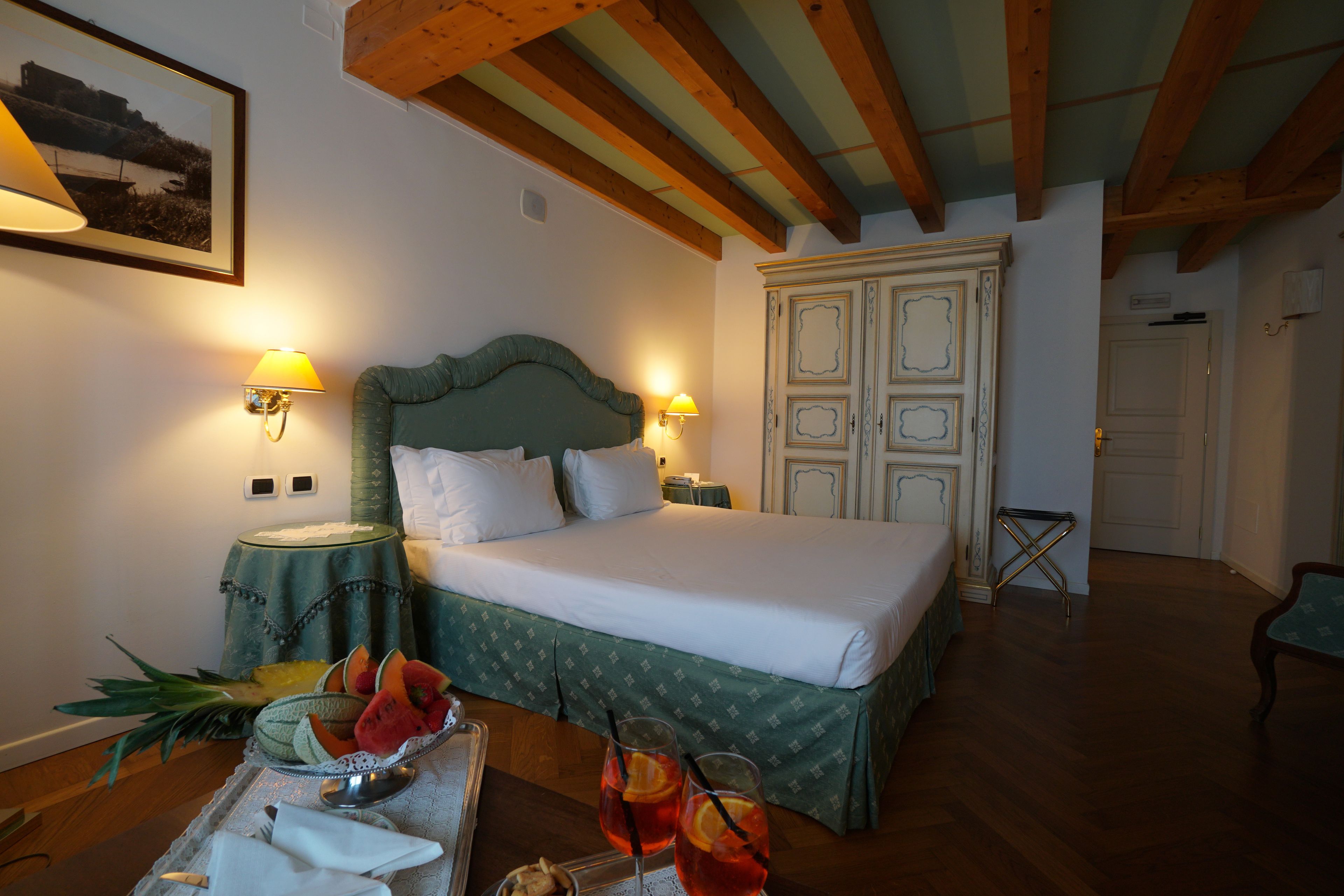 Une chambre à coucher avec un lit, des lampes de chevet, une table de nuit, un plateau avec des fruits et des boissons, et un plafond en bois.