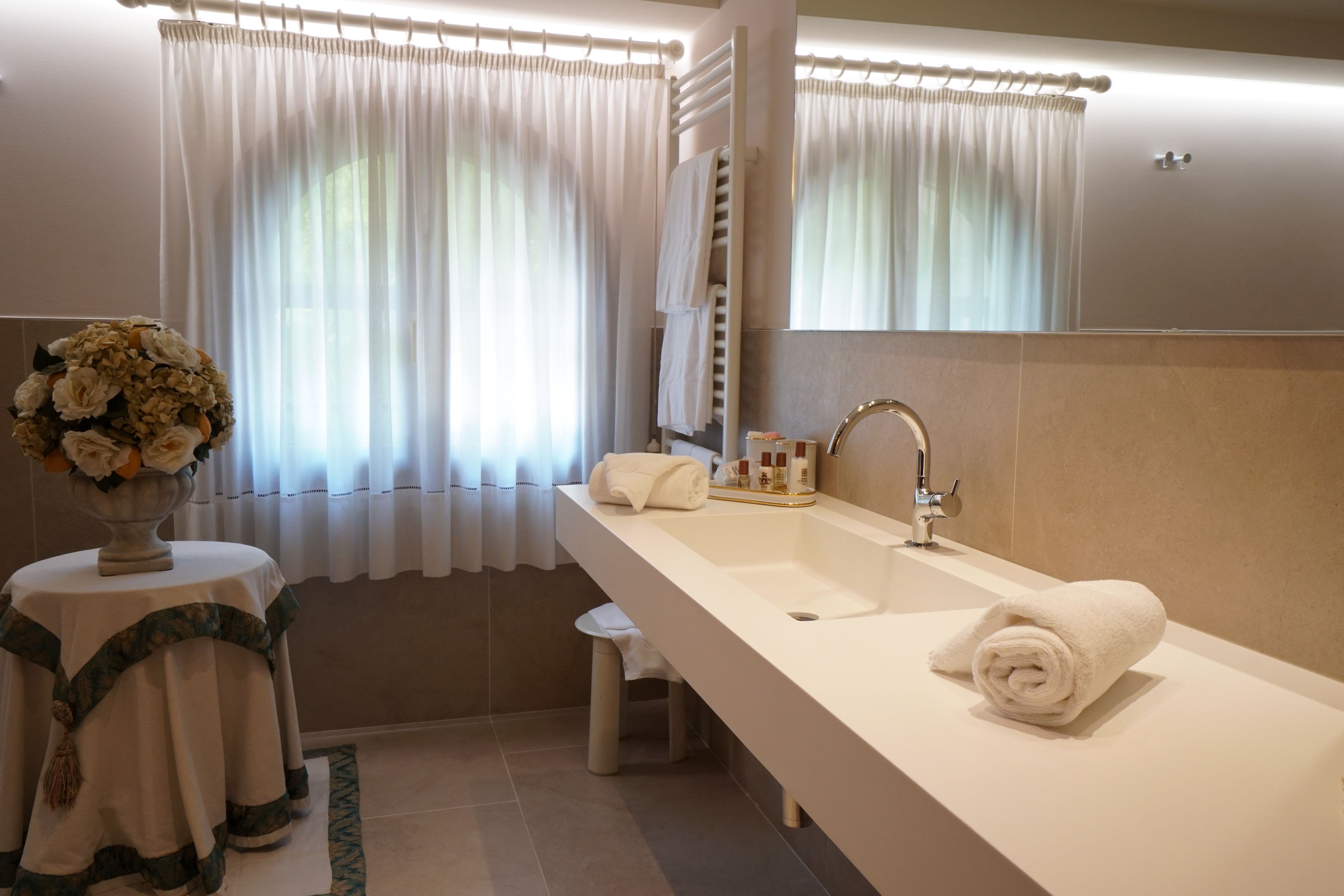 A modern bathroom with a large sink, a mirror, and a towel rack.