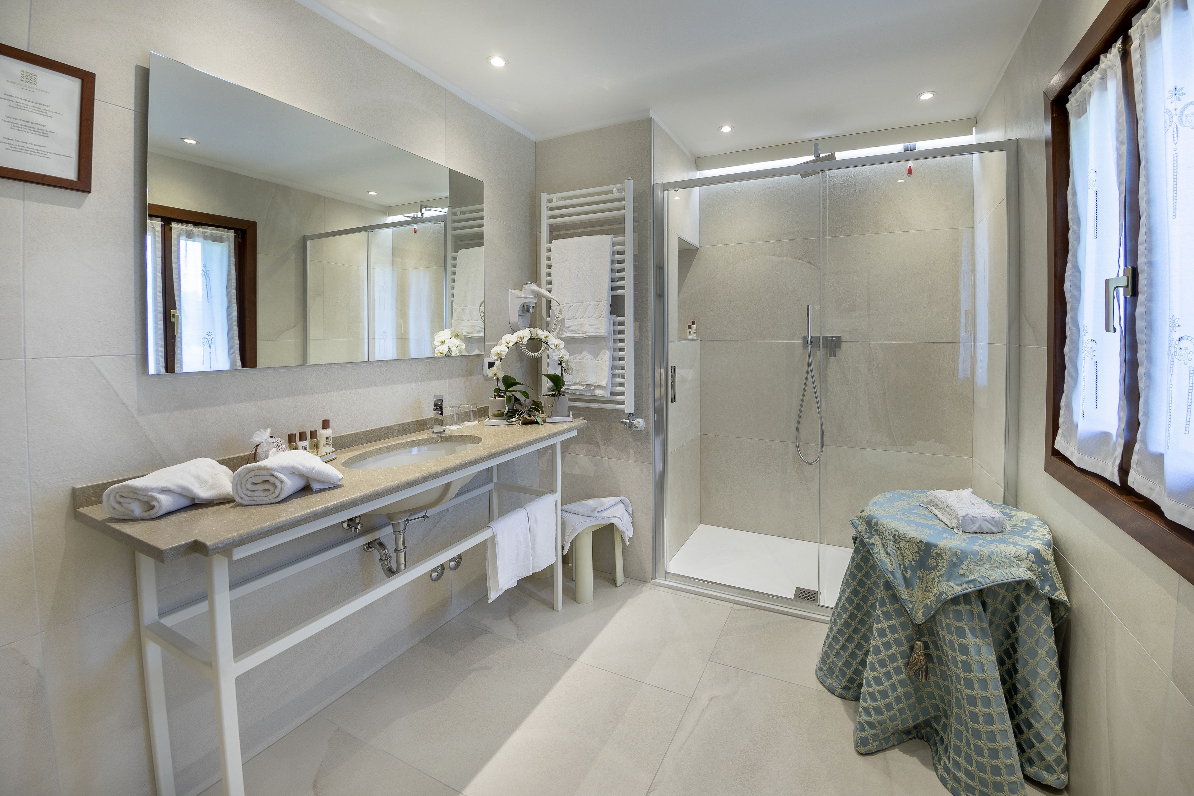 A modern bathroom with a large mirror, a shower area, and a vanity with a sink and towel rack.