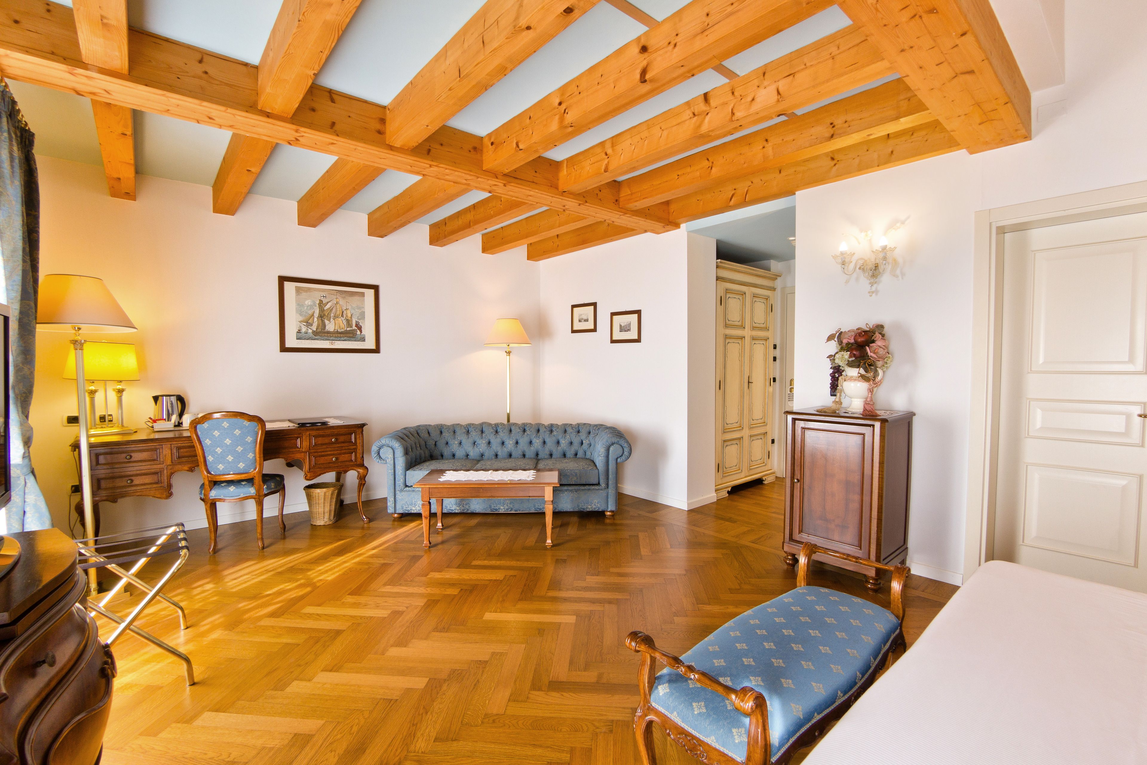 Ein Zimmer mit Holzbalken, einem blauen Sofa, einem Holzschrank und einer Lampe.