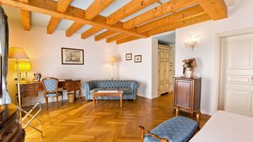 Ein Zimmer mit Holzbalken, einem blauen Sofa, einem Holzschrank und einer Lampe.