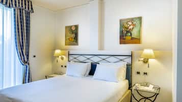 A neatly made bed with white linens, two wall-mounted lamps, and two paintings depicting flowers.