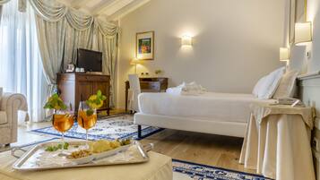 Habitación de hotel con cama, televisión, escritorio con lámpara y bandeja con bebidas y aperitivos.