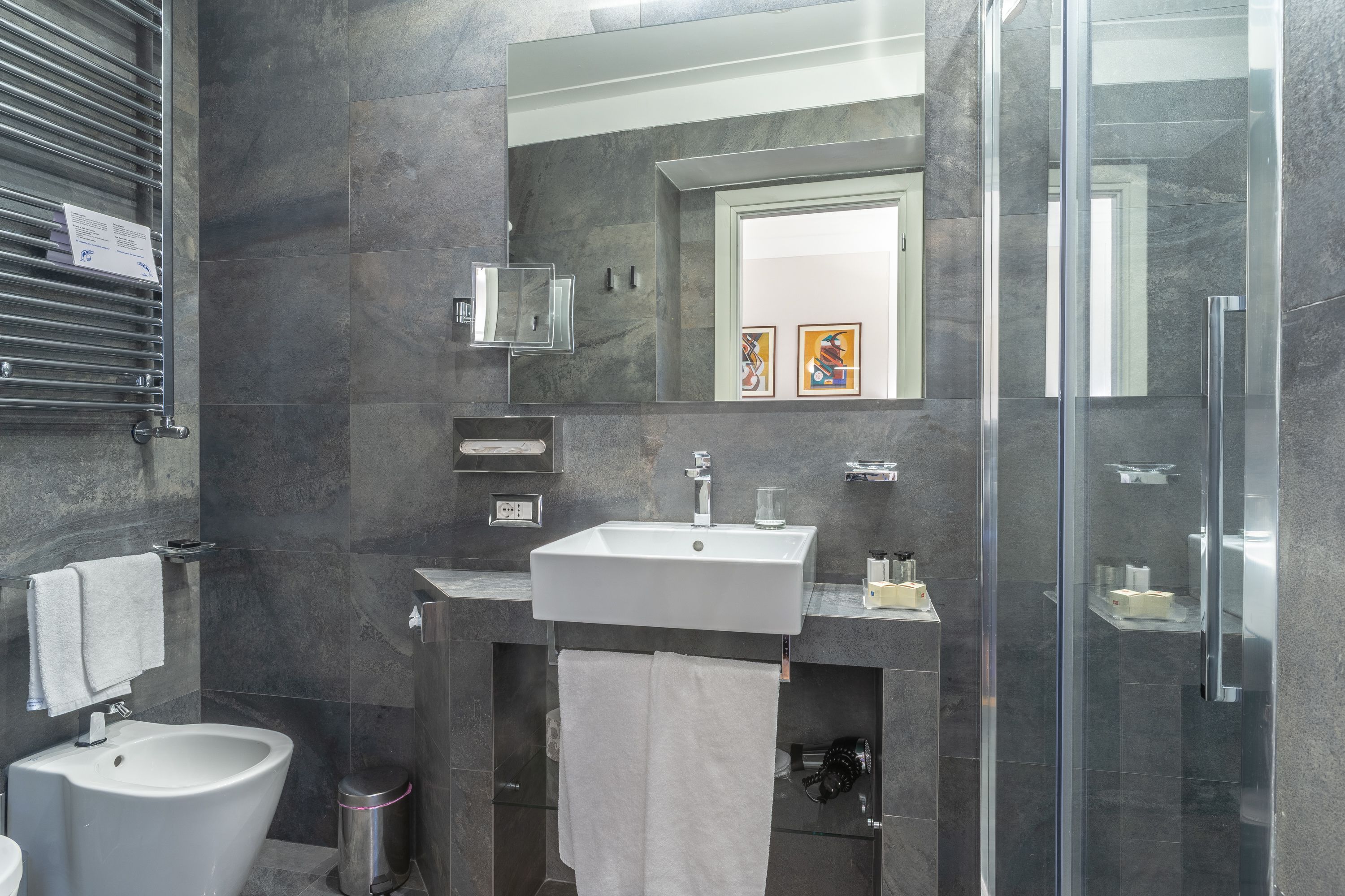 Une salle de bain moderne équipée d’un bidet, d’un lavabo et d’une douche à parois en verre.
