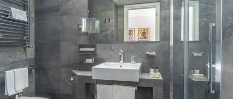 Une salle de bain moderne équipée d’un bidet, d’un lavabo et d’une douche à parois en verre.