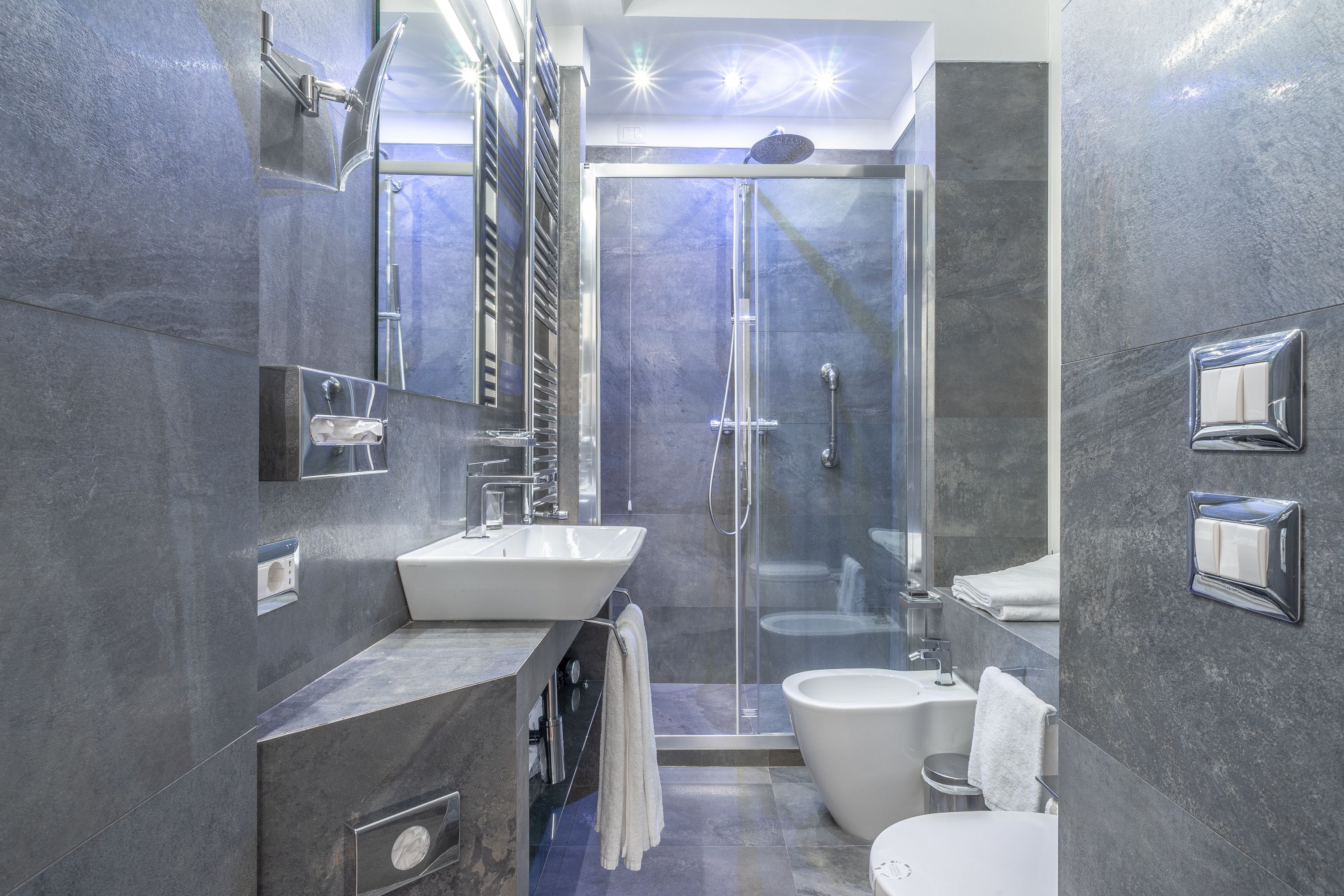 A modern bathroom with a glass-enclosed shower, a white sink, and a toilet.